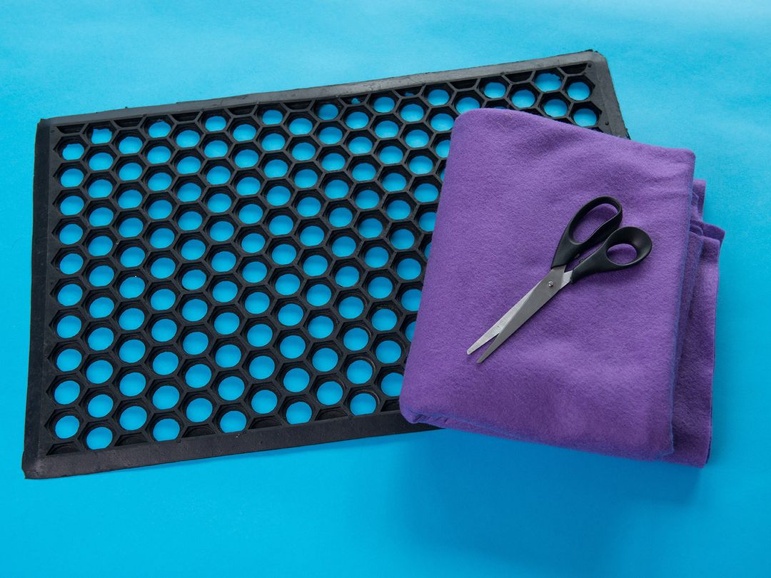Items needed for a snuffle mat including black mat with holes, felt and scissors
