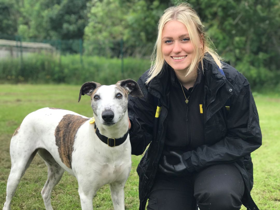 West Calder team member sitting with Greyhound outdoors