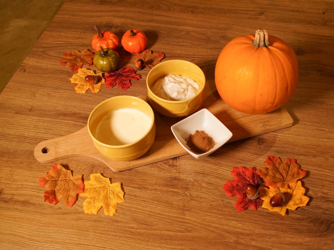 Photo of the ingredients needed to make a pumpkin spice pup-cup: a pumpkin, cinnamon, yoghurt and whipped cream.