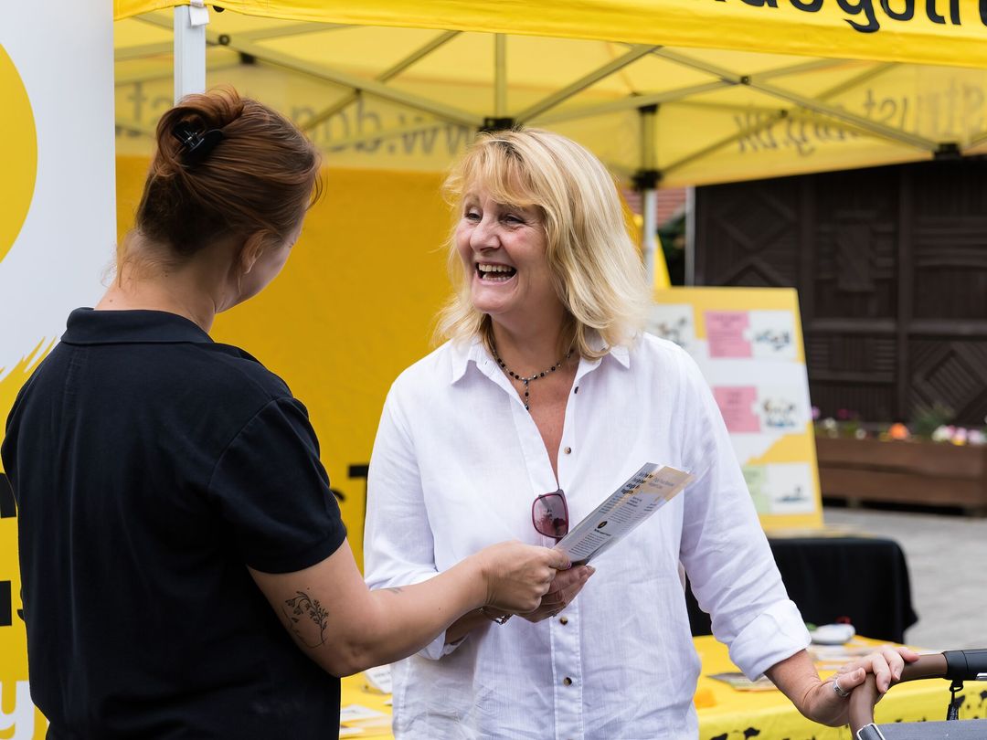 Woman with a pram being handed leaflets at a Dogs Trust community event