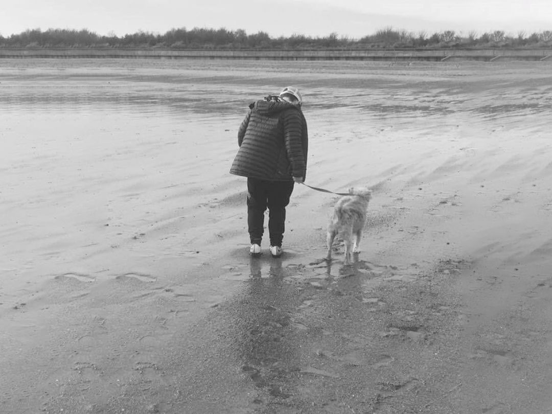 Black and white photo of Bradley and his dog on the beach