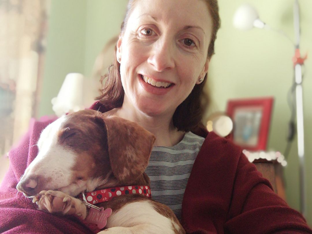Dixie the blind Dachshund in the arms of her owner Lucy smiling
