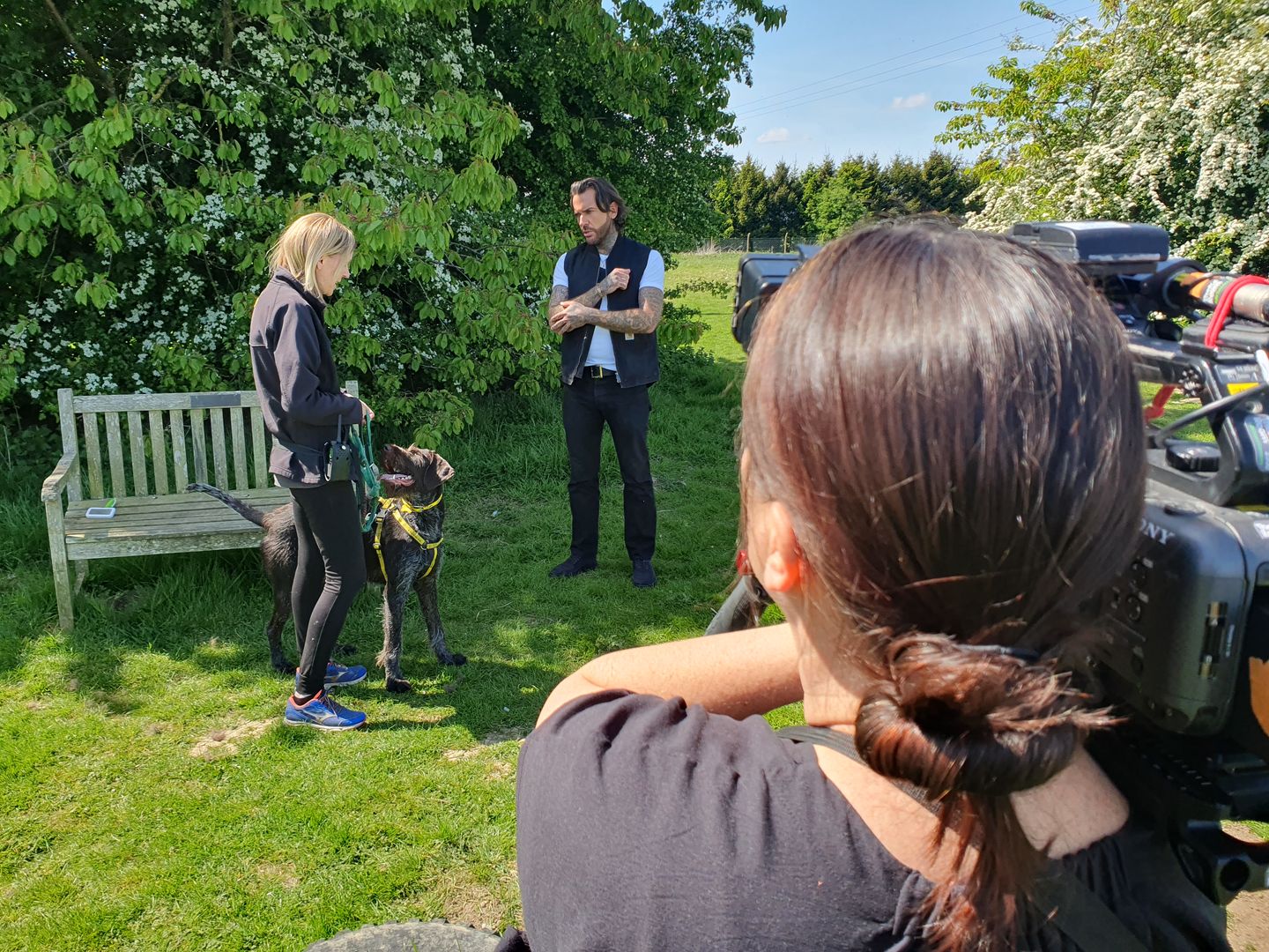 pete standing outside with a member of staff and a brown spotted crossbreed dog. they are being filmed