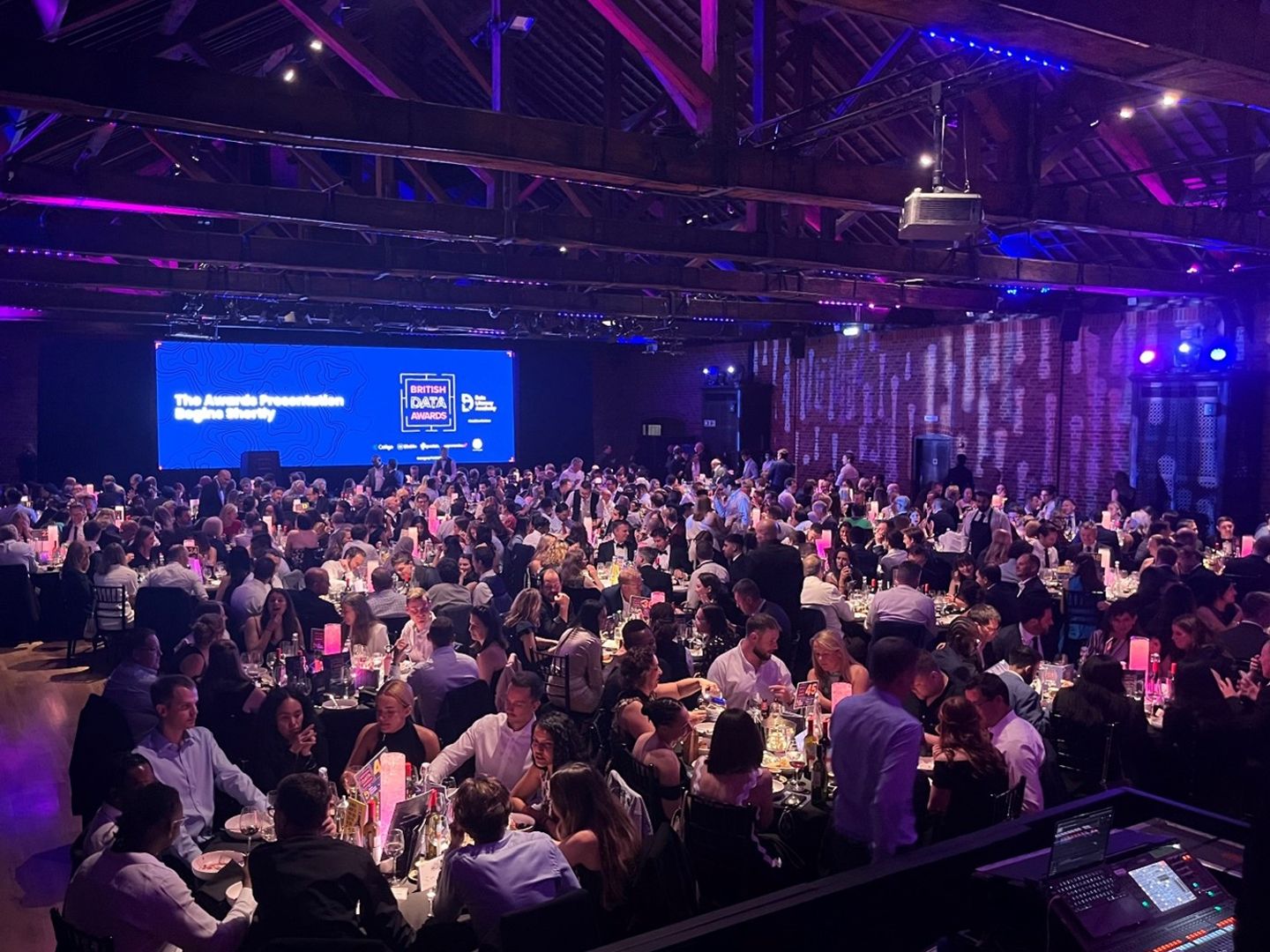 lots of people sitting down at the awards ceremony in a blue and purple lit room