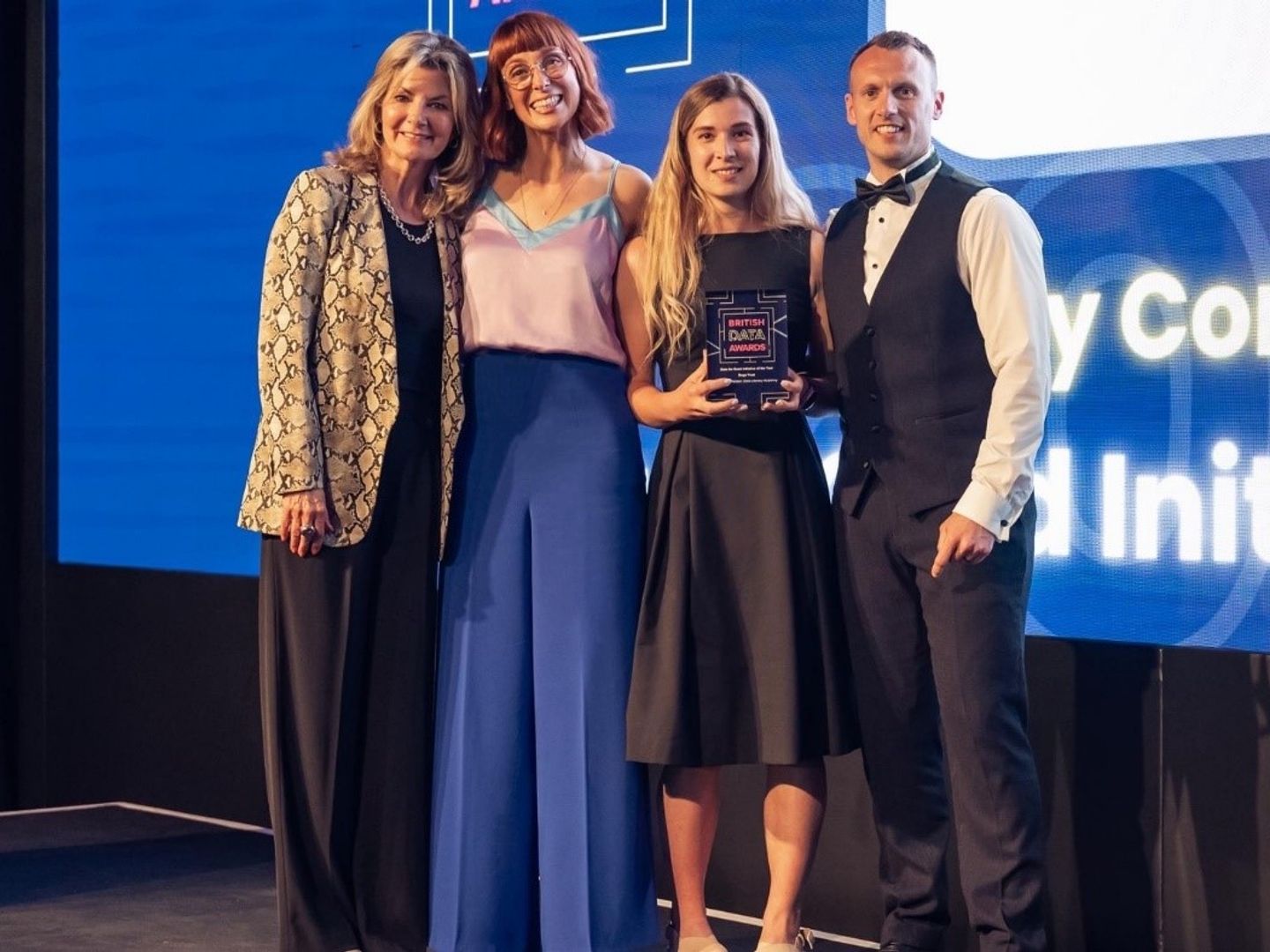 3 ladies and a man standing with the data awards trophy on stage