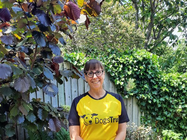 Dog lover Sue in dogs trust yellow and black t-shirt, smiling in a garden.