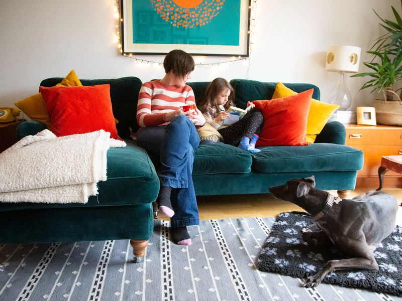 Adult female sitting on the sofa with child and greyhound on the floor