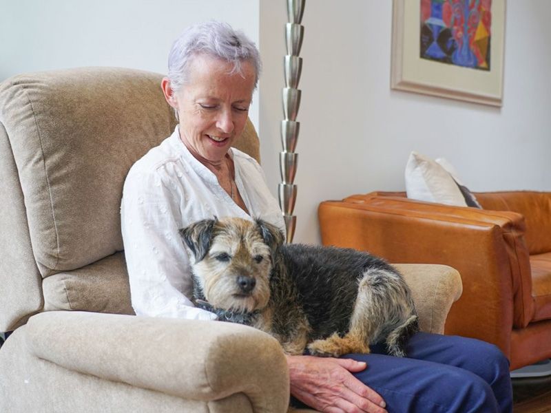 Dog sitting on a woman's lap as she looks down and smiles at him