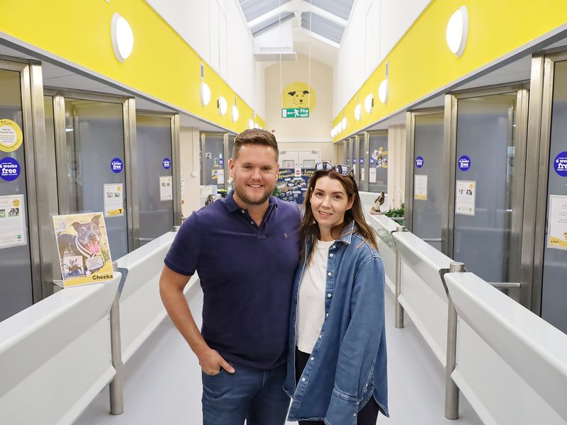 Simon Wilkes with his wife Kim smiling at the camera and standing in the kennel gallery, on their visit of the public viewing area of Dogs Trust Leeds.
