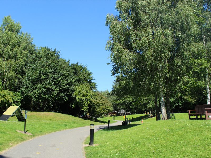 Merseyside Rehoming Centre exterior pathway with bench, green, path and play equipment.