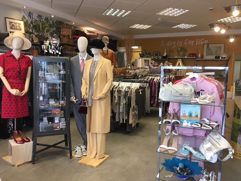 Inside Petersfield charity shop with lots of clothes mannequins and racks of clothes and bag displays