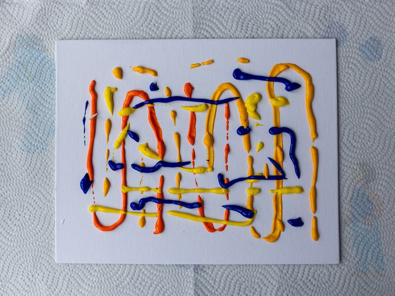 a white canvas with red, blue and yellow paint squiggled all over it