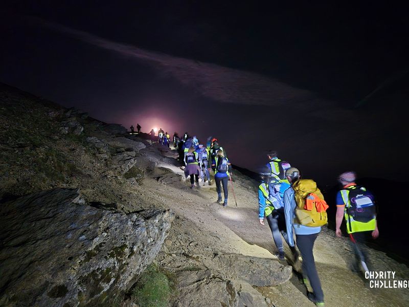 a line of hikers walking up Snowdon mountain at night