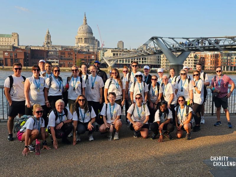 a big group of people taking a picture along the Thames, with St Pauls Cathedral and the Millennium bridge in the background