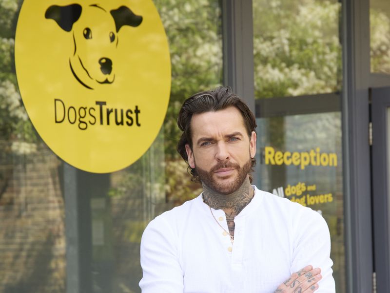 celebrity pete wicks standing outside basildon rehoming centre with our large dogs trust logo behind him