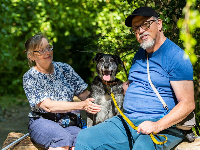 Toby the Underdog looks delighted as he sits with his adopters